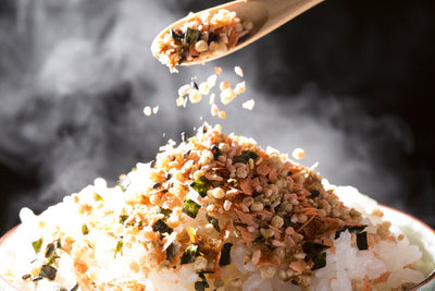 Furikake (a blend of dried herbs or fish, chili powder, dried sesame, and seaweed) being sprinkled over a piping hot bowl of rice.